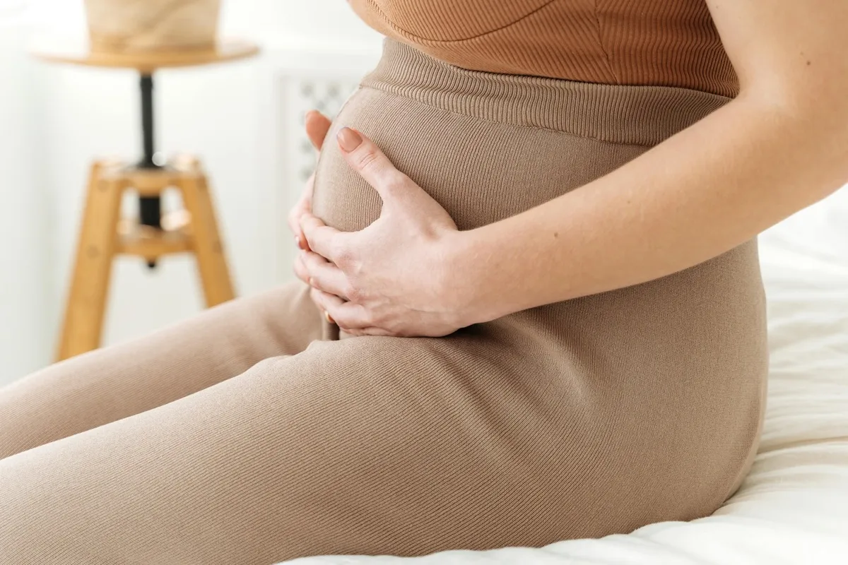Pregnant woman sitting and holding her belly