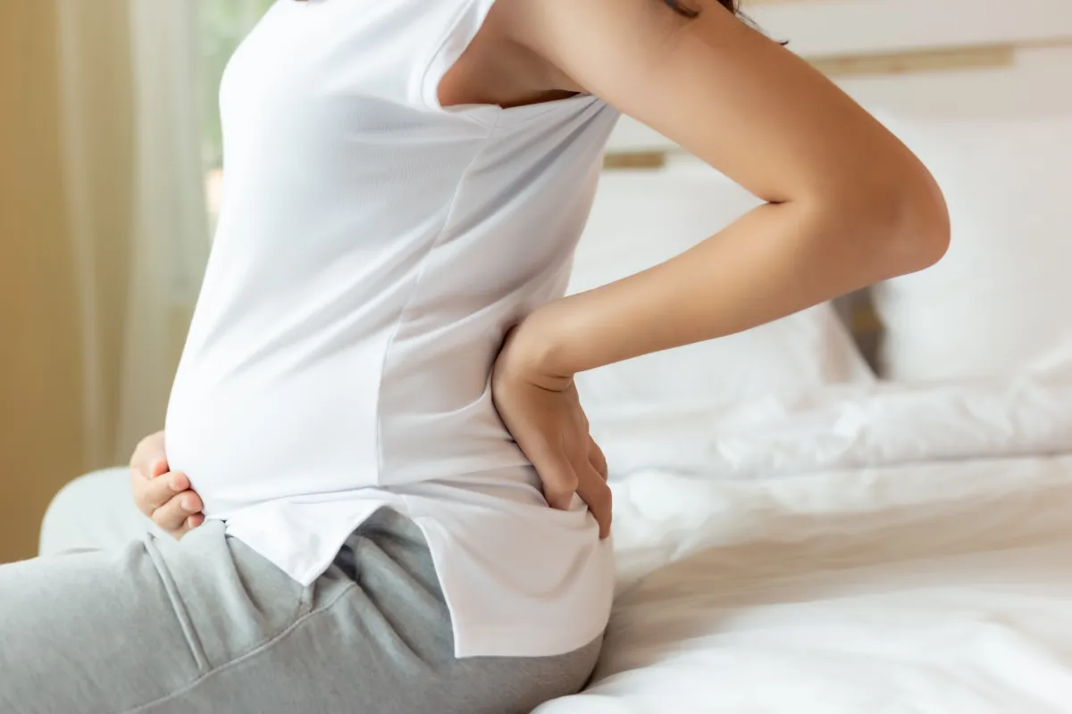 Pregnant woman holding her lower back in discomfort