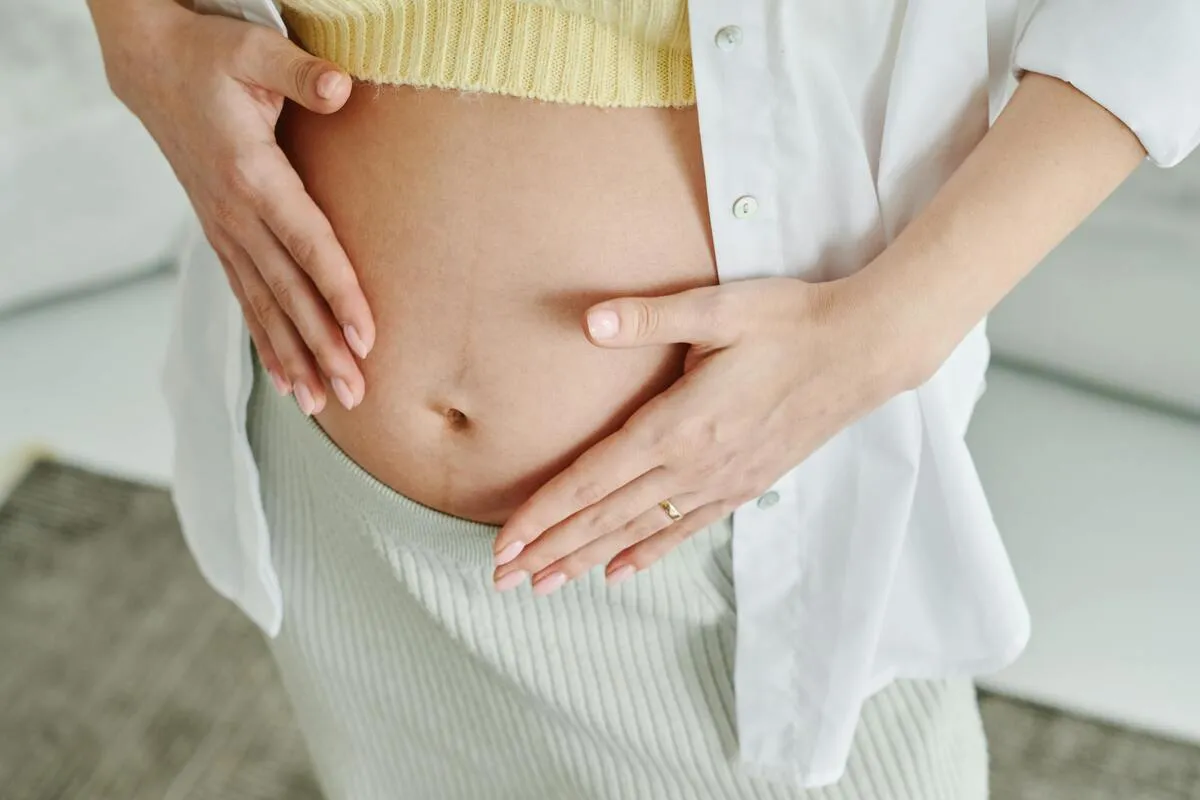 Pregnant woman holding her lower belly while resting comfortably