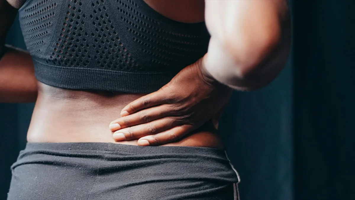 Person holding their lower back near the pelvis while experiencing SI joint pain